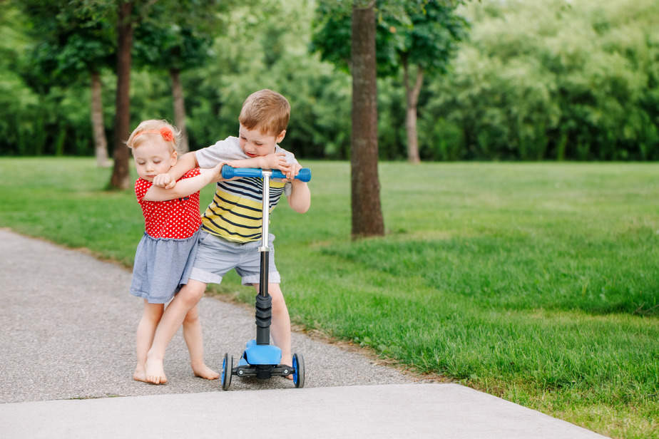 Canva – Two little Caucasian preschool children fighting hitting each other. Boy and girl can not share one scooter. Older sibling brother not giving his toy to younger sister. Communication problems.