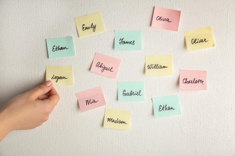 ביי פוסט צילום freepikchh puxy mhkuo FREEPIKfemale-hand-paper-stickers-with-different-names-white-wall-concept-choosing-baby-name